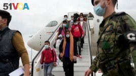 Afghan music students, faculty members and their families walk off an airplane at Lisbon military airport, Monday, Dec. 13, 2021. A group of 273 students, faculty members and their families from the Afghanistan National Institute of Music arrived Monday i