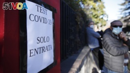 A directional sign at a COVID-19 testing site is seen near a growing line of test seekers in the northern Italian town of Bozen on Friday, November 20, 2020. (AP Photo/Antonio Calanni)