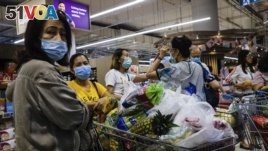 Shoppers wearing face masks with a cart full of food supplies wait in line to pay at a supermarket counter in Singapore, Tuesday, Mar. 17, 2020. (AP Photo/Ee Ming Toh)