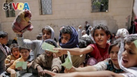 Yemenis present documents in order to receive food rations provided by a local charity, in Sanaa, Yemen. (File)