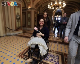 Sen. Tammy Duckworth, D-Ill., with her baby Maile Pearl Bowlsbey leaves the Senate floor after a voting on Capitol Hill in Washington, Thursday, April 19, 2018. (AP Photo/Manuel Balce Ceneta)