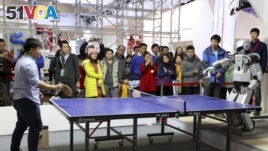 People watch as a robot (R) plays table tennis with a man during an demonstration at the World Robot Conference in Beijing, China, Nov. 2015. (FILE PHOTO)