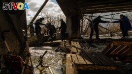 Civilians in Irpin escape from the battles through an improvised path created alongside a bombed bridge by Ukrainian forces in Ukraine, March 8, 2022. (Yan Boechat/VOA) 