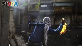 FILE - A Palestinian protester throws a Molotov cocktail towards Israeli soldiers during conflicts in the West Bank city of Hebron, April 3, 2013. (AP Photo/Nasser Shiyoukhi, File)