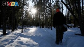 Frank Manthey follows E.J. Isaac and Roger Deschampe Jr. into the Grand Portage, Minn. woods on March 2, 2022. (AP Photo/Emma H. Tobin)