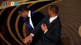 Will Smith, right, hits presenter Chris Rock on stage while presenting the award for best documentary feature at the Oscars on Sunday, March 27, 2022, at the Dolby Theatre in Los Angeles. (AP Photo/Chris Pizzello)
