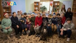 Children traumatized by the war pose for photo with an American Pit Bull Terrier Bice in the Center for Social and Psychological Rehabilitation in Boyarka close Kyiv, Ukraine, Wednesday, Dec. 7, 2022. (AP Photo/Vasilisa Stepanenko)