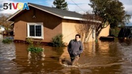 Nick Enero wades through floodwaters while helping his brother salvage items from his Merced, Calif., home as storms continue battering the state on Jan. 10, 2023. (AP Photo/Noah Berger)