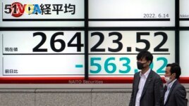 Men wearing masks walk past an electronic stock board showing Japan's Nikkei 225 index Tuesday, June 14, 2022, in Tokyo. Asian shares fell Tuesday after Wall Street tumbled into a bear market. (AP Photo/Shuji Kajiyama)
