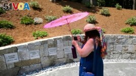 FILE - Karla Hailer, a fifth-grade teacher from Scituate, Massachusetts takes a video on July 19, 2017, where a memorial stands at the site where women were executed as witches. (AP Photo/Stephan Savoia, File)