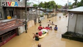 People wade through a flooded street in San Miguel town, Philippines, Sept. 26, 2022. Typhoon Noru went through northern Philippines on Monday, leaving several dead, causing floods and power outages. (AP Photo/Aaron Favila)