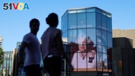 People walk by as a tribute to Queen Elizabeth appears on the National Arts Centre, after Queen Elizabeth's passing, in Ottawa, Ontario, Canada, September 8, 2022. REUTERS/Patrick Doyle