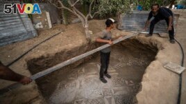Palestinians clean around a Byzantine-era mosaic floor that was uncovered recently by a farmer in Bureij in central Gaza Strip, Sept. 5, 2022. (AP Photo/Fatima Shbair)