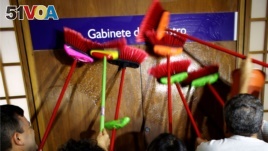 Ministerial staff use brooms to scrub the office door of the Transparency Minister Fabiano Silveira demanding his resignation, in Brasilia, Brazil, Monday, May 30, 2016. A recording TV Globo broadcast late Sunday shows Silveira criticizing Operation Car Wash, a wide-ranging corruption probe of the state oil company Petrobras that has implicated numerous leading Brazilian politicians and businessmen. Protesters in Brazil use brooms as a representation to sweep away corruption. (AP Photo/Eraldo Peres)