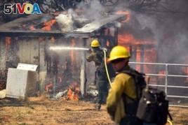 Firefighters battle flames as a house burns in Lower Lake, Calif., on Aug. 14, 2016. The fire reached Main Street in Lower Lake, a town of about 1,200 about 90 miles north of San Francisco