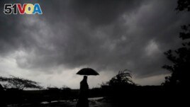 FILE - A villager under dark clouds in Balasore area in Odisha, India on May 25, 2021, ahead of a powerful storm heading toward the eastern coast. (AP Photo/File)