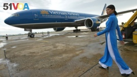 FILE - A Vietnam Airlines employee walks out to greet a newly delivered Boeing 777-200ER at Noi Bai airport in Hanoi, Vietnam on Sunday Sept. 19, 2004. (AP Photo/Richard Vogel)