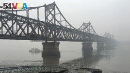 FILE - Trucks move across the bridge linking North Korea with the Chinese border city of Dandong in this March 3, 2016 photo. 