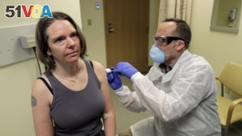 A pharmacist gives Jennifer Haller, left, the first shot in the first-stage safety study clinical trial of a potential vaccine for COVID-19, the disease caused by the new coronavirus, Monday, March 16, 2020, in Seattle. (AP Photo/Ted S. Warren)