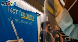 Los Angeles Unified Superintendent Austin Beutner takes pictures with high school students, as a Licensed Vocational Nurse prepares Pfizer vaccines. (AP Photo/Damian Dovarganes)
