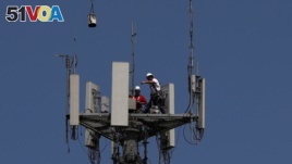 Workers install 5G telecommunications equipment on a T-Mobile tower in Seabrook, Texas, May 6, 2020.