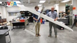 Aerospace engineering doctoral student Adrien Bouskela (left) and professor Sergey Shkarayev hold an experimental sailplane. The team hopes to one day send a version of a similar plane to Mars. (Image Credit: Emily Dieckman/College of Engineering)