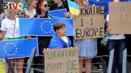 Protestors in support of Ukraine stand with signs and EU flags during a demonstration outside of an EU summit in Brussels, Thursday, June 23, 2022. (AP Photo/Olivier Matthys)