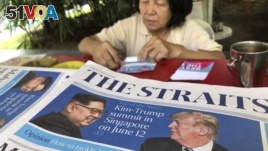 A news vendor counts her money near a stack of newspapers with a photo of U.S. President Donald Trump, right, and North Korea's leader Kim Jong Un on its front page on Friday, May 11, 2018, in Singapore.