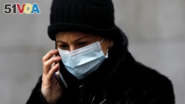 A woman in a surgical mask uses her cellphone after more cases of coronavirus were confirmed in Manhattan, New York City, New York, U.S., March 11, 2020. REUTERS/Andrew Kelly