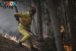 A firefighter works on an active fire on a hillside outside the village of Monchique, in southern Portugal's Algarve region, Monday, Aug. 6, 2018.