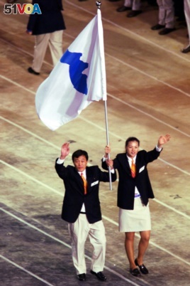 FILE - In this Sept. 15, 2000, file photo, Pak Jung Chul, left, a North Korea's Judo coach, and Chung Eun-sun, a South Korean basketball player, carry a flag representing a united Korea into Olympic Stadium during the Opening Ceremony of the Olympics.
