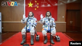 Chinese astronauts Jing Haipeng (L) and Chen Dong wave in front of a Chinese national flag before the launch of Shenzhou-11 manned spacecraft, in Jiuquan, China, October 17, 2016. REUTERS/Stringer 