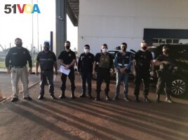 Personnel of the General Directorate of Migration, agents of the Paraguayan office of INTERPOL and members of the Federal Police of Brazil pose for a photo, during the handover of Brazilian citizen Chelbe Willams Moraes in an unknown location, June 7, 2021.