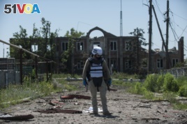 An OSCE monitor checks the territory for mines during a patrol in Shyrokyne, Donetsk region eastern Ukraine, Saturday, July 4, 2015. (AP Photo)