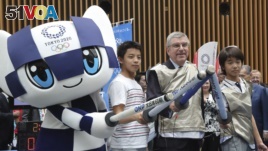 IOC President Thomas Bach poses for a photo with Japanese junior high school student Yui Hashimoto, right, and Yuto Tojima, second from left, and Miraitowa, mascot of Tokyo 2020 during a Olympic Games Tokyo 2020 One year to Go ceremony event in Tokyo, Wednesday, July 24, 2019. 