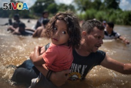 A man, part of a caravan of migrants from Central America en route to the United States, carries a girl through the Suchiate River into Mexico from Guatemala in Ciudad Hidalgo, Mexico, Oct. 29, 2018.