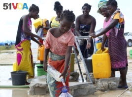 A young girl fetches water at a camp for displaced survivors of cyclone Idai in Beira, Mozambique, April, 2, 2019.