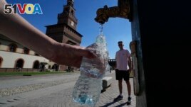 FILE - Tourists fill plastic bottles with water from a public fountain at the Sforzesco Castle, in Milan, Italy, June 25, 2022. (AP Photo/Luca Bruno, File)