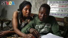 FILE - In this Saturday, Sept. 26, 2020 file photo, Miriam Nyambura helps her son Peter Kihika, 16, who wants to become a teacher.