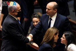 Benjamin Netanyahu (L) greets new Israel Prime minister Naftali Bennett following the vote on the new coalition at the Knesset, Israel's parliament, in Jerusalem June 13, 2021. (REUTERS/Ronen Zvulun)