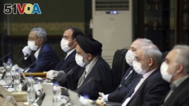 In this photo released by the official website of the Office of the Iranian Presidency, cabinet members wearing face masks and gloves attend their meeting in Tehran, Iran, Wednesday, March 18, 2020. 