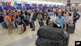 People push their bags as others stand in line after flights resumed Monday, Aug. 8, 2016, in Salt Lake City, following a computer outage. Delta Air Lines delayed or canceled hundreds of flights Monday after its computer systems crashed, stranding thousands of people on a busy travel day. (AP Photo/Rick Bowmer)