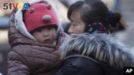 FILE - A Chinese woman cuddles her child in Beijing. China announced Thursday it was ending its long-standing one-child policy and will now allow all couples to have two children. (2014 AP PHOTO)