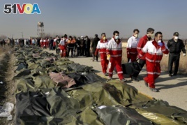Rescue workers carry the body of a victim of a Ukrainian plane crash in Shahedshahr, southwest of the capital Tehran, Iran, Wednesday, Jan. 8, 2020.