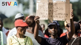 FILE - An unemployed man holds up a sign at the Sugar Ray Xulu stadium in Clermont township, north of Durban, May 1, 2019. (Photo by RAJESH JANTILAL / AFP)