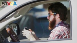 FILE - An man works his phone as he drives through traffic in Dallas, Tuesday, Feb. 26, 2013. Texas lawmakers are considering a statewide ban on texting while driving. (AP Photo/LM Otero)