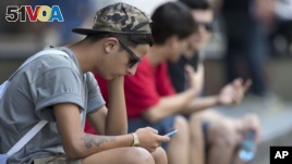 A youth checks his cell phone in Sao Paulo, Brazil, Dec. 17, 2015. 