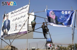Afghan men installs election posters of parliamentarian candidates during the elections campaign for the upcoming election in Kabul, Afghanistan, Oct. 9, 2018.