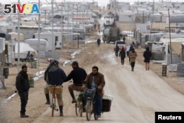 Syrian refugees travel on the main street of Al Zaatari refugee camp in the Jordanian city of Mafraq, near the border with Syria, Jan. 15, 2015.
