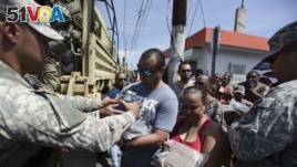 National Guardsmen arrive at Barrio Obrero in Santurce to distribute water and food among those affected by the passage of Hurricane Maria, in San Juan, Puerto Rico, Sept. 24, 2017.
